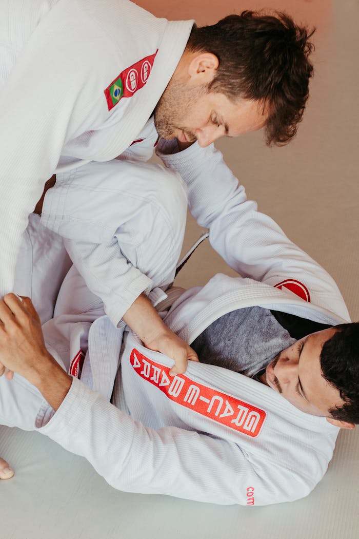 Two men practicing Brazilian Jiu-Jitsu grappling indoors in a training session.